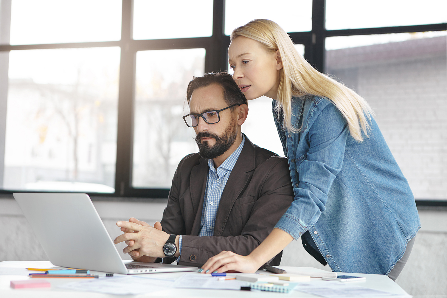 Two male and female freelance coworkers or colleagues discuss ideas about developing startup project, look at website, think how improve it, use laptop computer and wireless internet connection